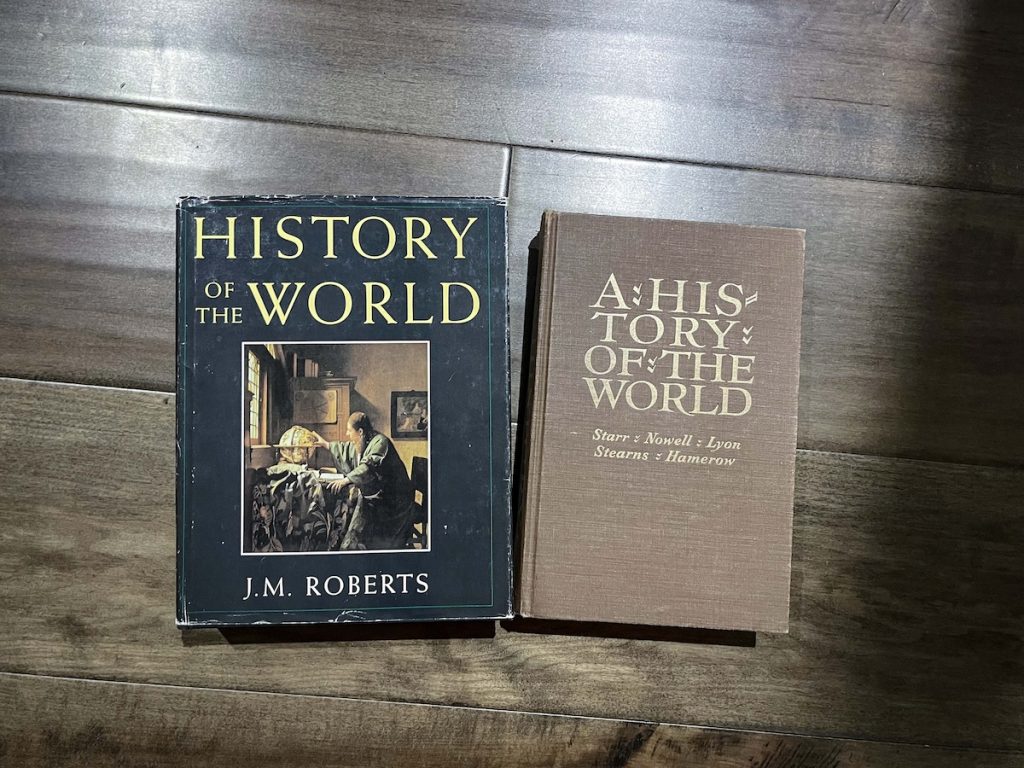 Two books placed on the floor. One is titled, "History of the World" by J.M. Roberts and the other is "A History of the World" by Starr, Nowell, Lyon, Stearns, and Hamerow. 