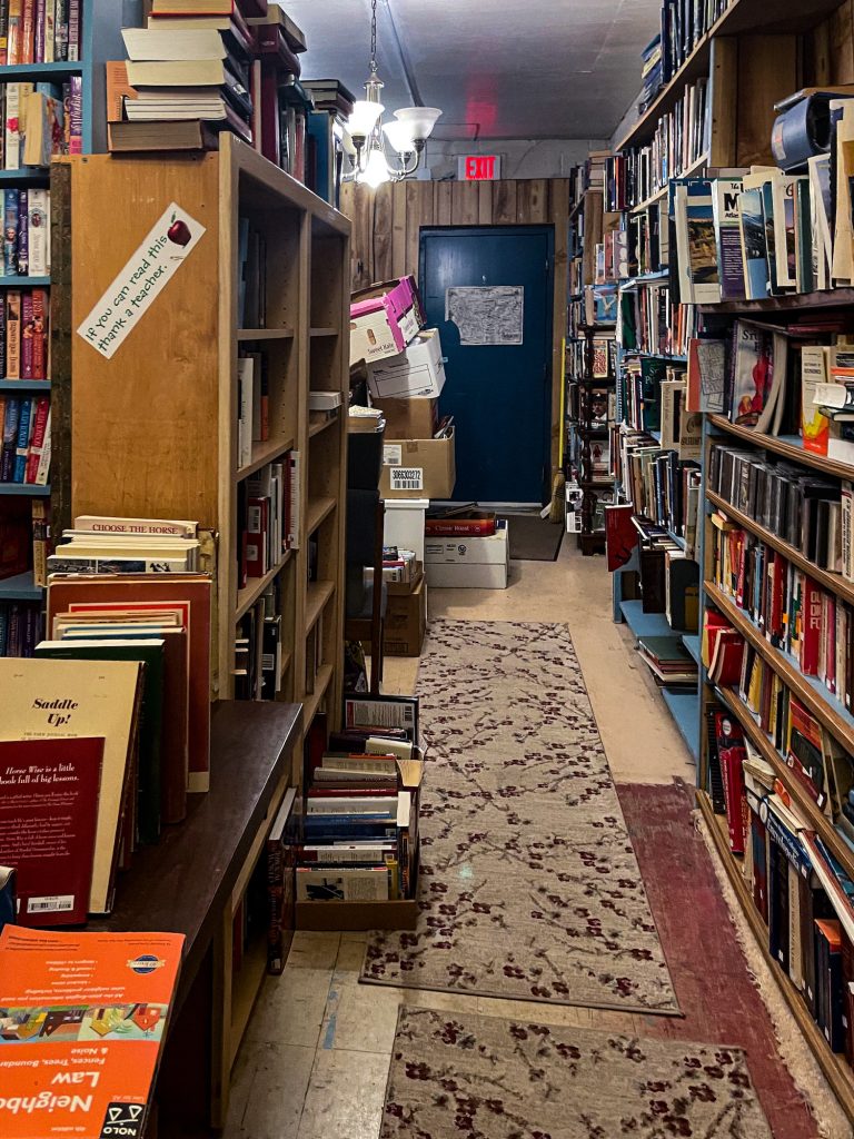 cute hallway with bookshelves and stacks of books on either side off of the second room