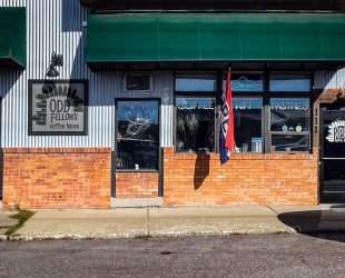 the front door of Odd Fellows that has a bluish metal exterior with red bricks for the bottom 1/3