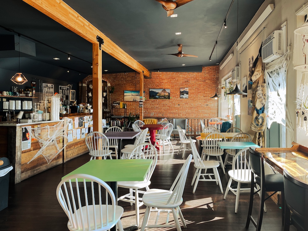 interior of Odd Fellows Coffee House. About six tables, each with a different color sitting to the right of the cashier and menu section where they make the coffee